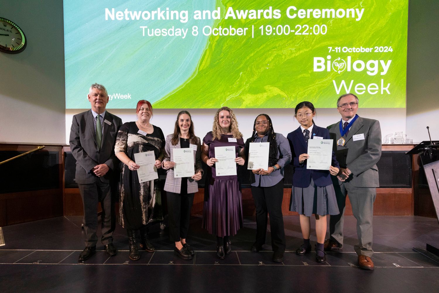 RSB CEO and President standing either side of group of awardees holding their certificates on stage at Biology Week 2024